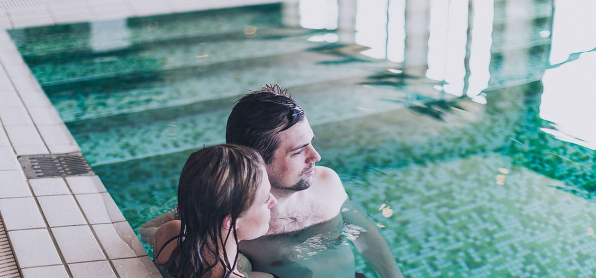 Man och kvinna står i poolen på Smögens Hafvsbad spaavdelning, spapaket morgonsol, aftonbris och heldagsnjutning